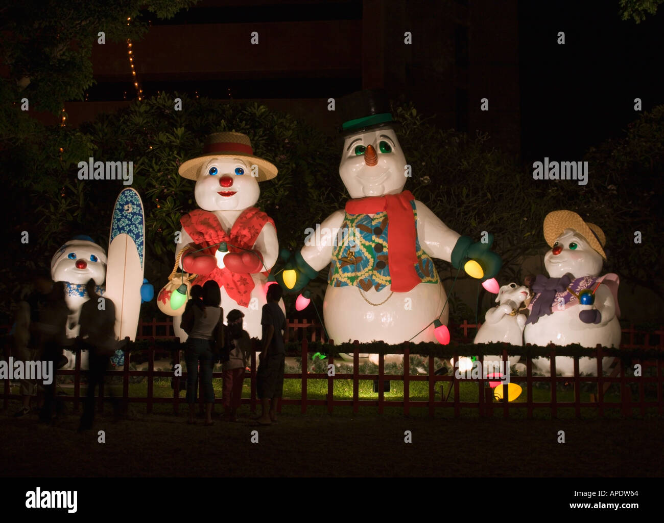 Four big toy model Christmas characters of a snowman family illuminated at night in central Honolulu Oahu Island Hawaii Stock Photo
