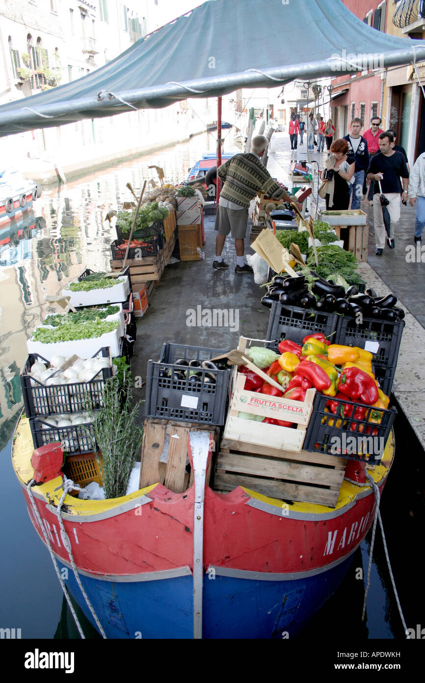 Man selling groceries from a small boat in Venice, Italy Stock Photo