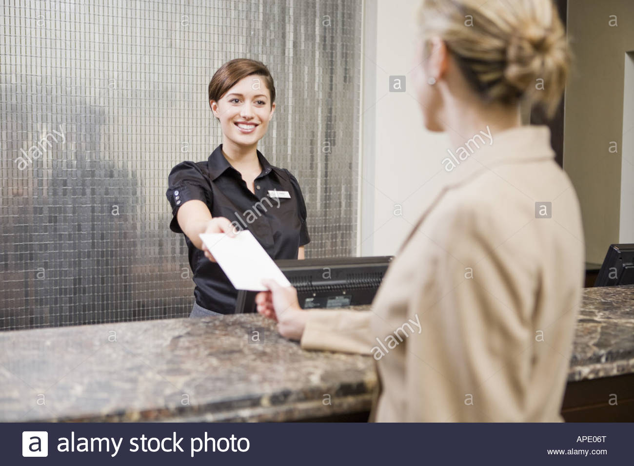 Businesswoman Checking In At Hotel Front Desk Stock Photo