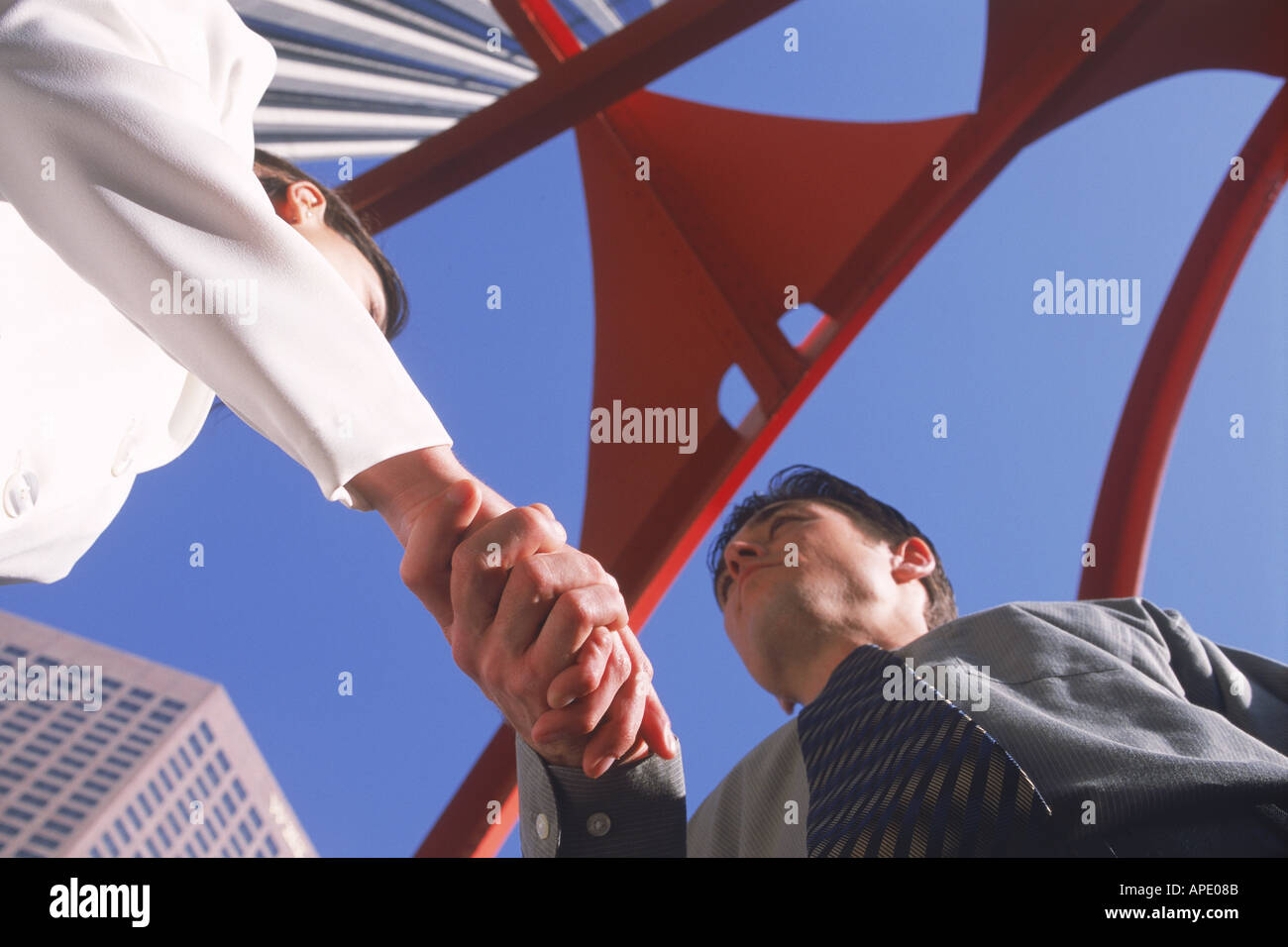 Businessman and woman shaking hands under Four Arches sculpture designed in1974 by Alexander Calder in downtown Los Angeles Stock Photo
