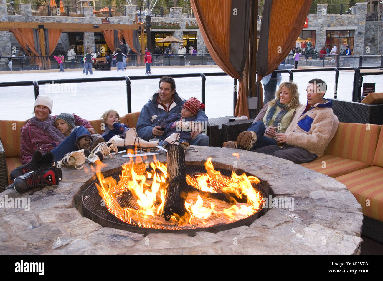 A family and friends sitting next to a fire at the ice rink at Northstar ski resort near Lake Tahoe in California Stock Photo