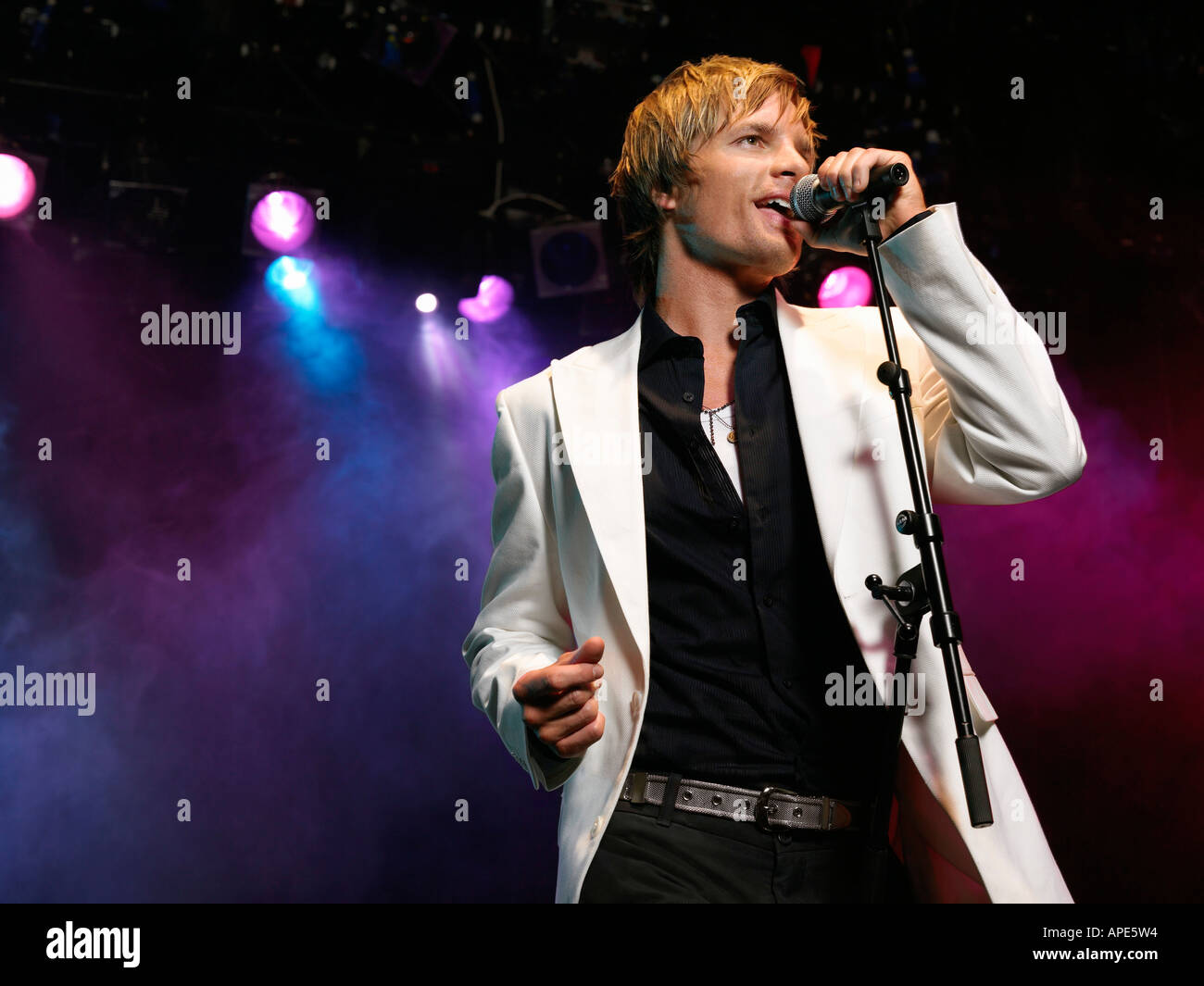 Young Man Singing into microphone on stage at Concert, low angle view Stock Photo