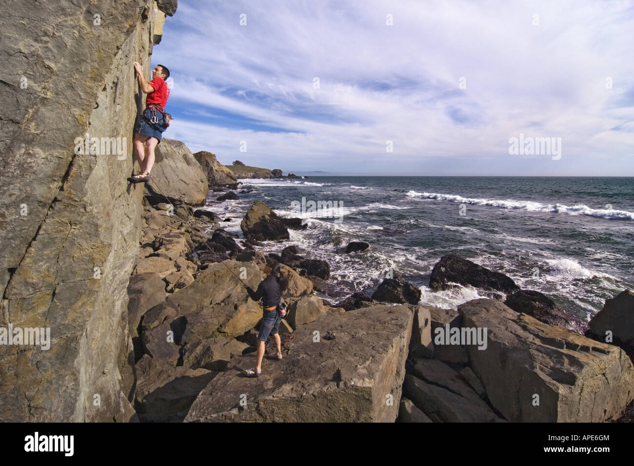 A man and a woman rock climbing next to the Pacific Ocean at Mickey's Beach near Stinson Beach in California Stock Photo