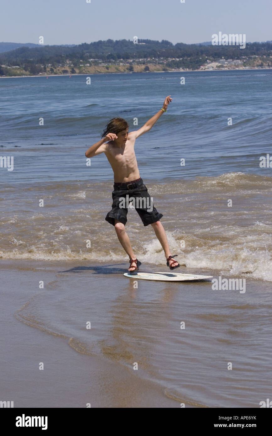 A young boy skim boarding on the beach on the Pacific Ocean in Santa Cruz, California Stock Photo