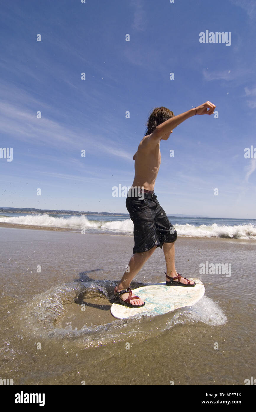 A young boy skim boarding on the beach on the Pacific Ocean in Santa Cruz, California Stock Photo