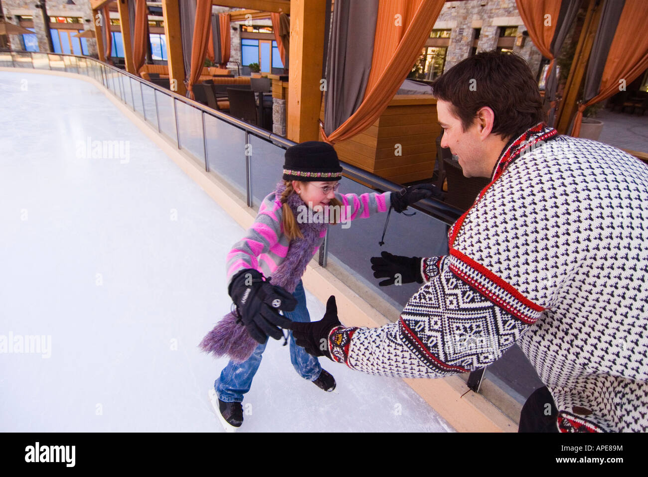 A father holding out his arms for his daughter as she skates towards him at Northstar ski resort near Lake Tahoe in California Stock Photo