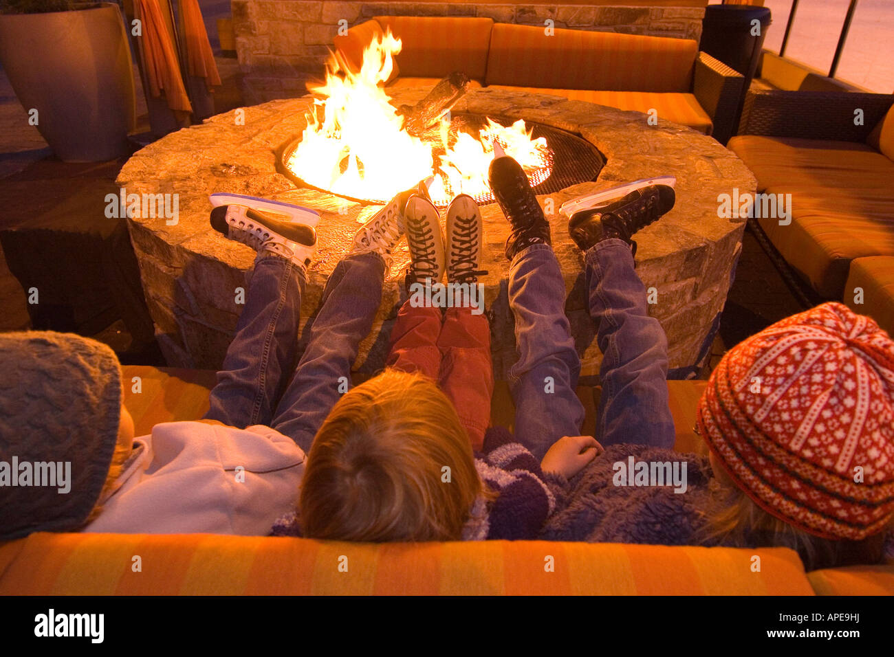 Three children relaxing next to a fire at an ice skating rink at Northstar ski resort near Lake Tahoe in California Stock Photo