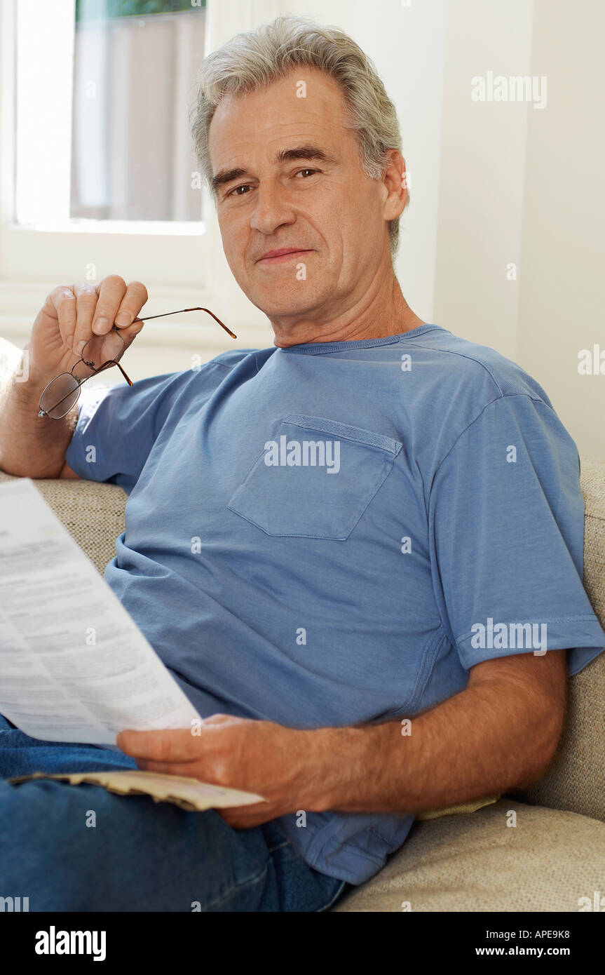 Man holding spectacles and bill, looking at camera Stock Photo