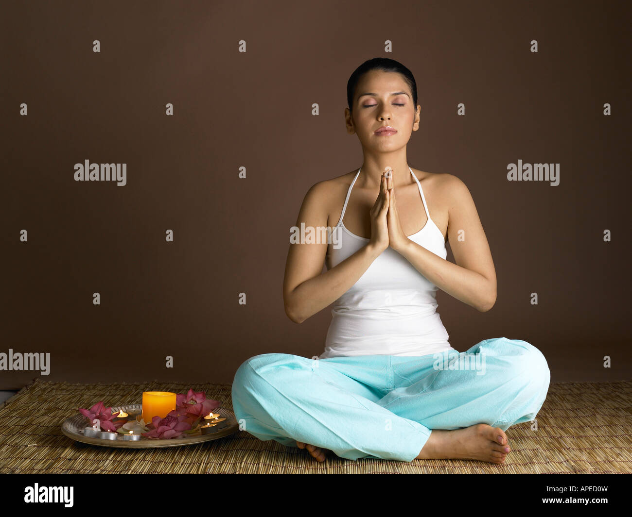South Asian Indian woman praying with prayer utensil wearing white top and cyan pant MR # 702 Stock Photo