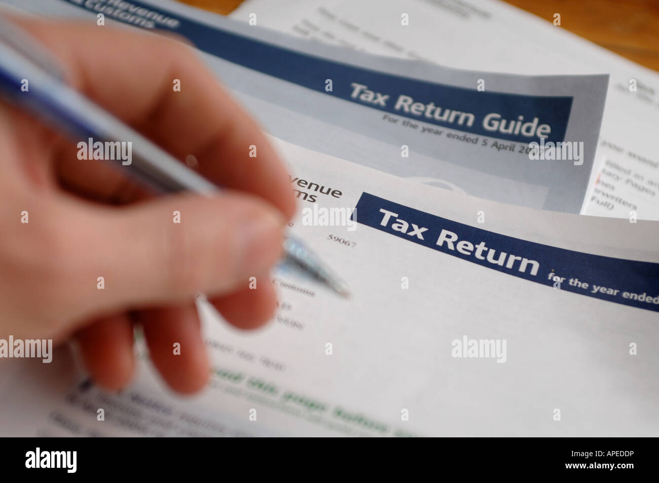 A hand seen filling in the Tax Return form using the tax return guide