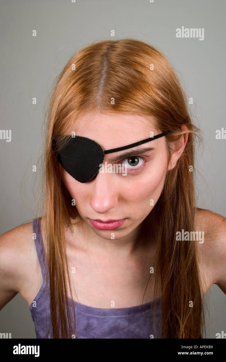 Young woman, with long red hair, wearing an eye patch and making faces.  MODEL RELEASED. Stock Photo
