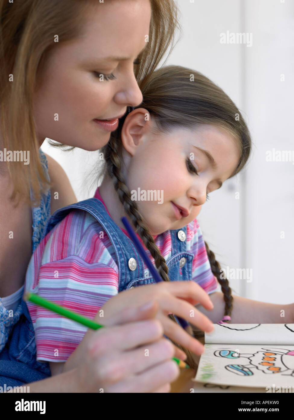 Mother and daughter (3-4) colouring in book, at home Stock Photo