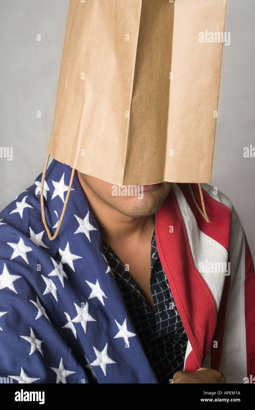 Portrait Latino man wrapped in American flag with brown bag on head Stock Photo