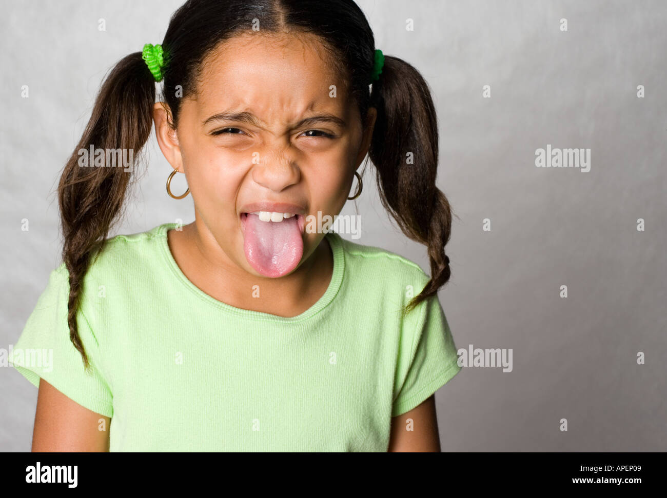Portrait Latino girl sticking out tongue Stock Photo