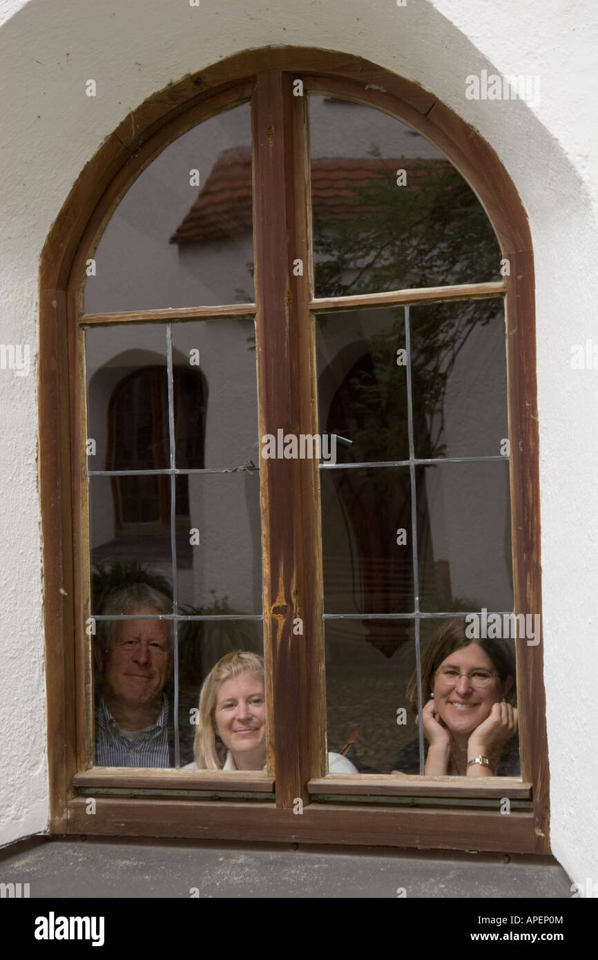 Tourists smile out the old window of a monastary. Stock Photo