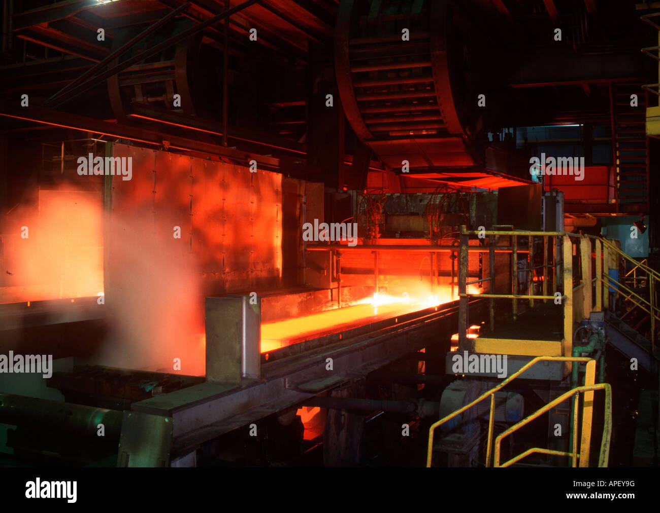 Red-hot flat steel slabs emerge from hot rolling mill at Siderar steel mill Stock Photo