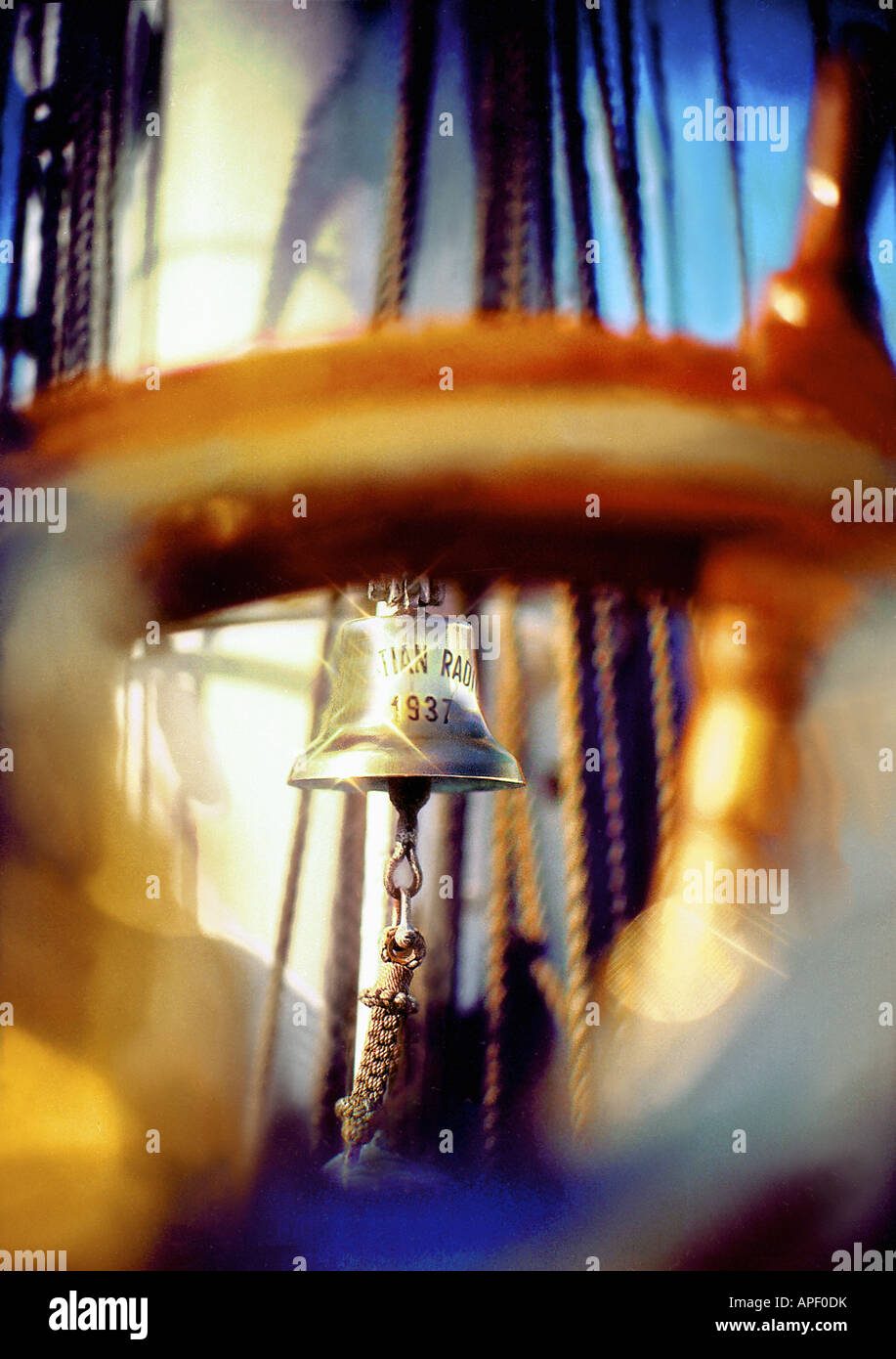 Ship's bell seen through ship steering wheel with ropes rigging and ...