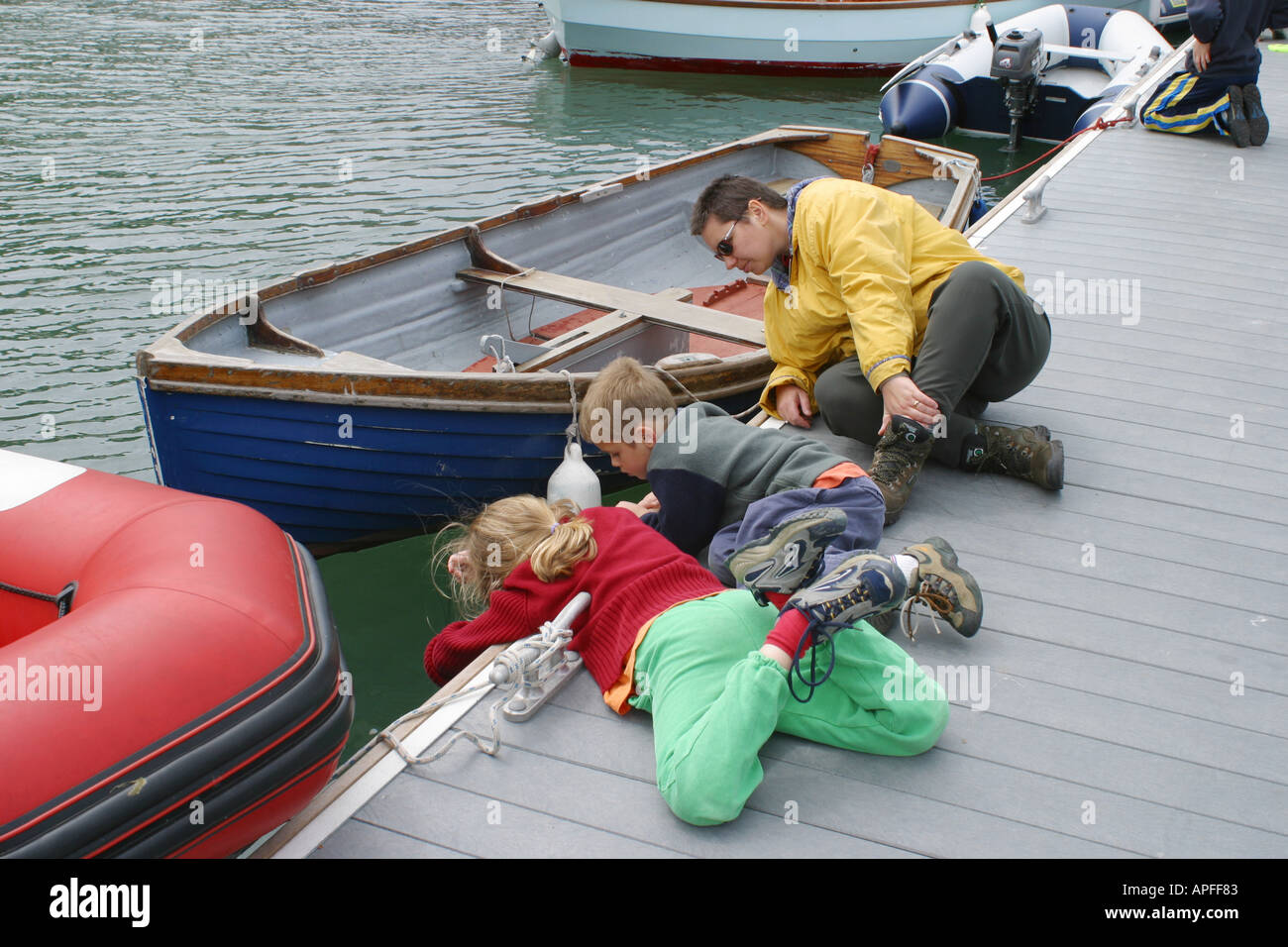 Family crab fishing lying on a jetty in Dale Pembrokeshire Wales
