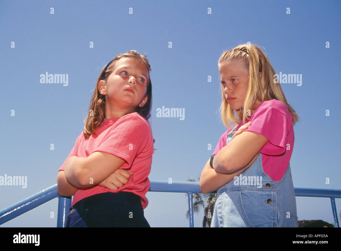 Two young school girls 8-10 years old of age angry with each other looks over shoulder with mean expression low angle from below  MR ©Myrleen Pearson Stock Photo