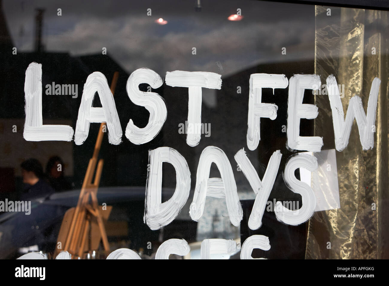 last few days painted white paint inside window shop closing down with customers inside Belfast Stock Photo