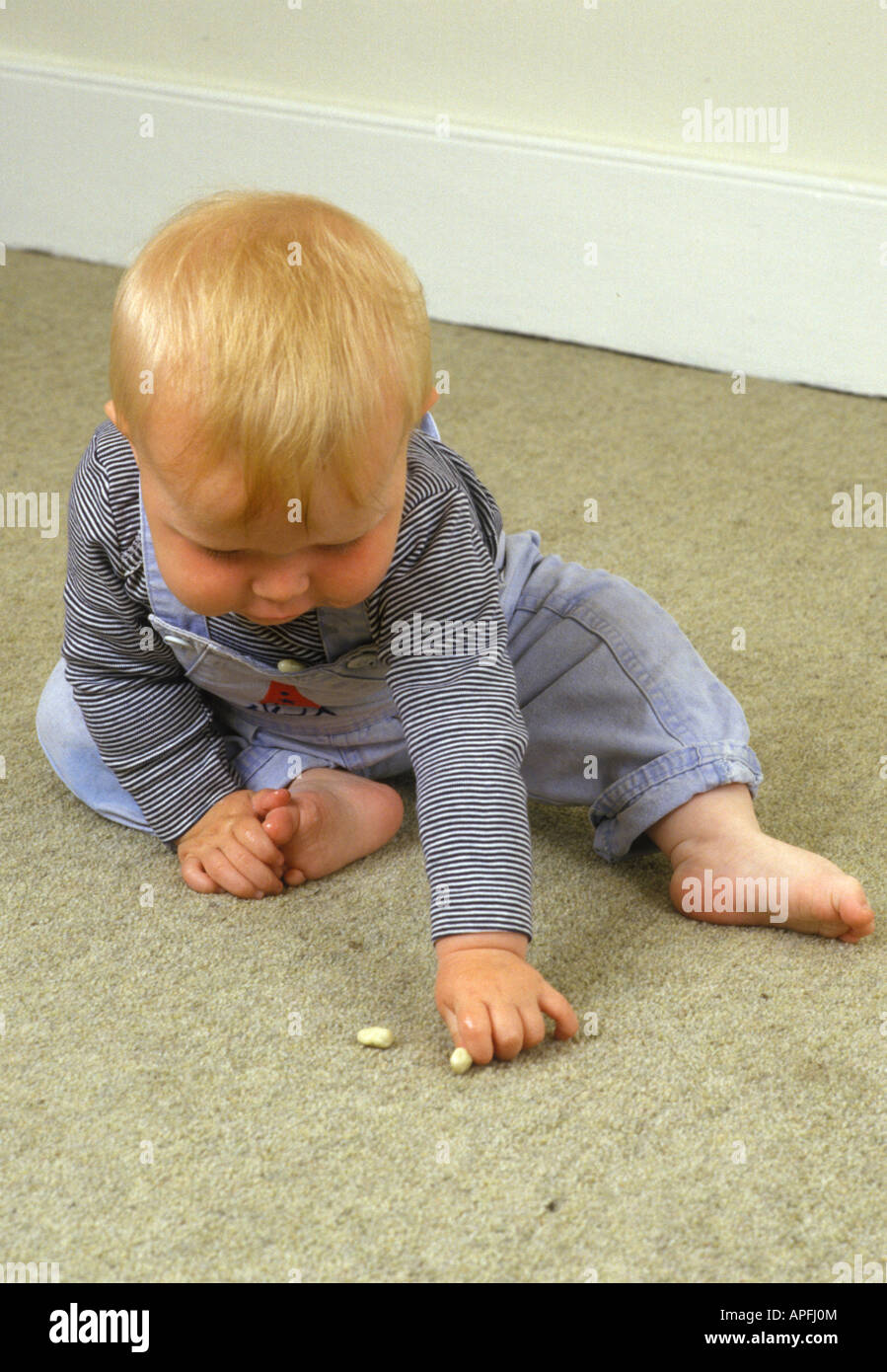 baby picking up object on carpet Stock Photo