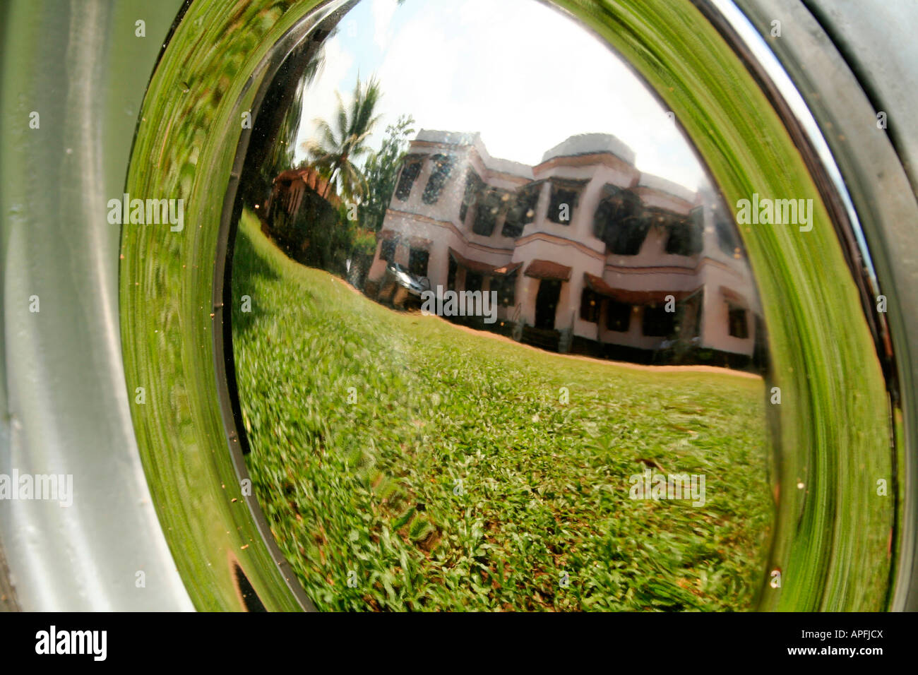 Typical big old house with well maintained lawn in Kerala, reflected on the silver plated wheel-cup of an ambassador car Stock Photo