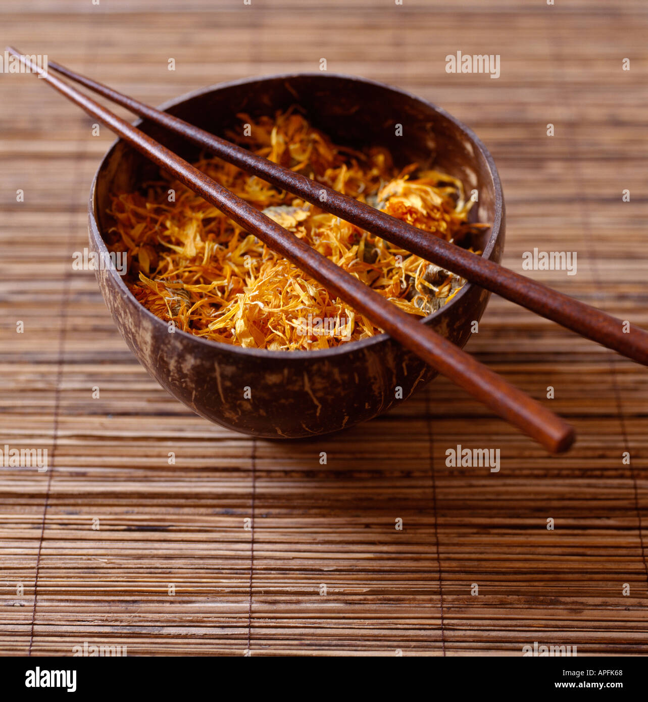 Dried marigold flowers in coconut bowl with chopsticks Stock Photo