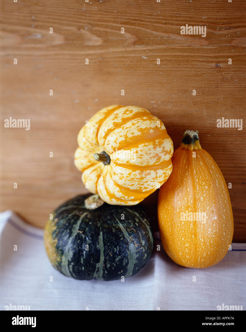 Selection of three squashes on table cloth with wooden background Stock Photo
