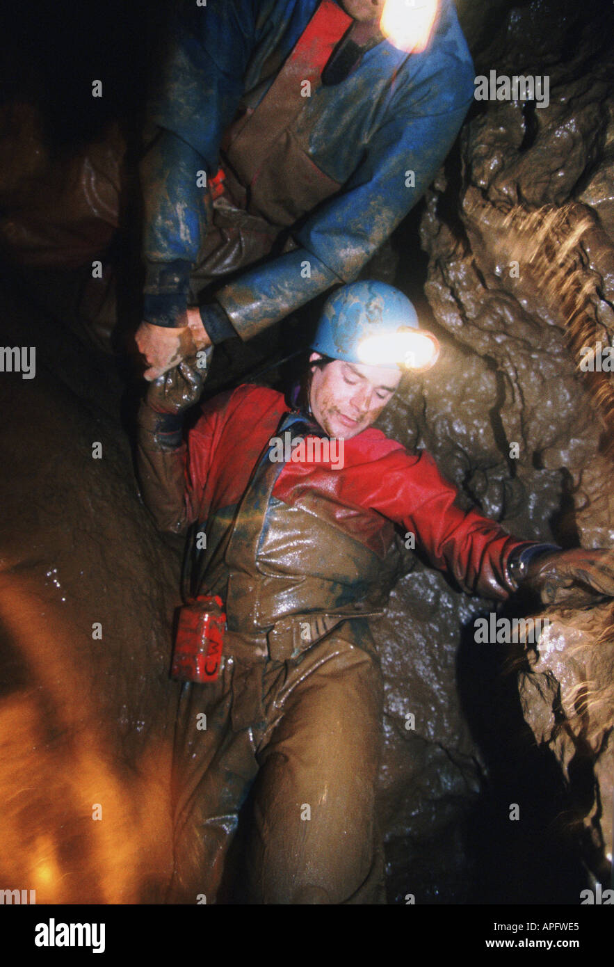 Woman pot holing in mud, underground cave, Devon, UK Stock Photo