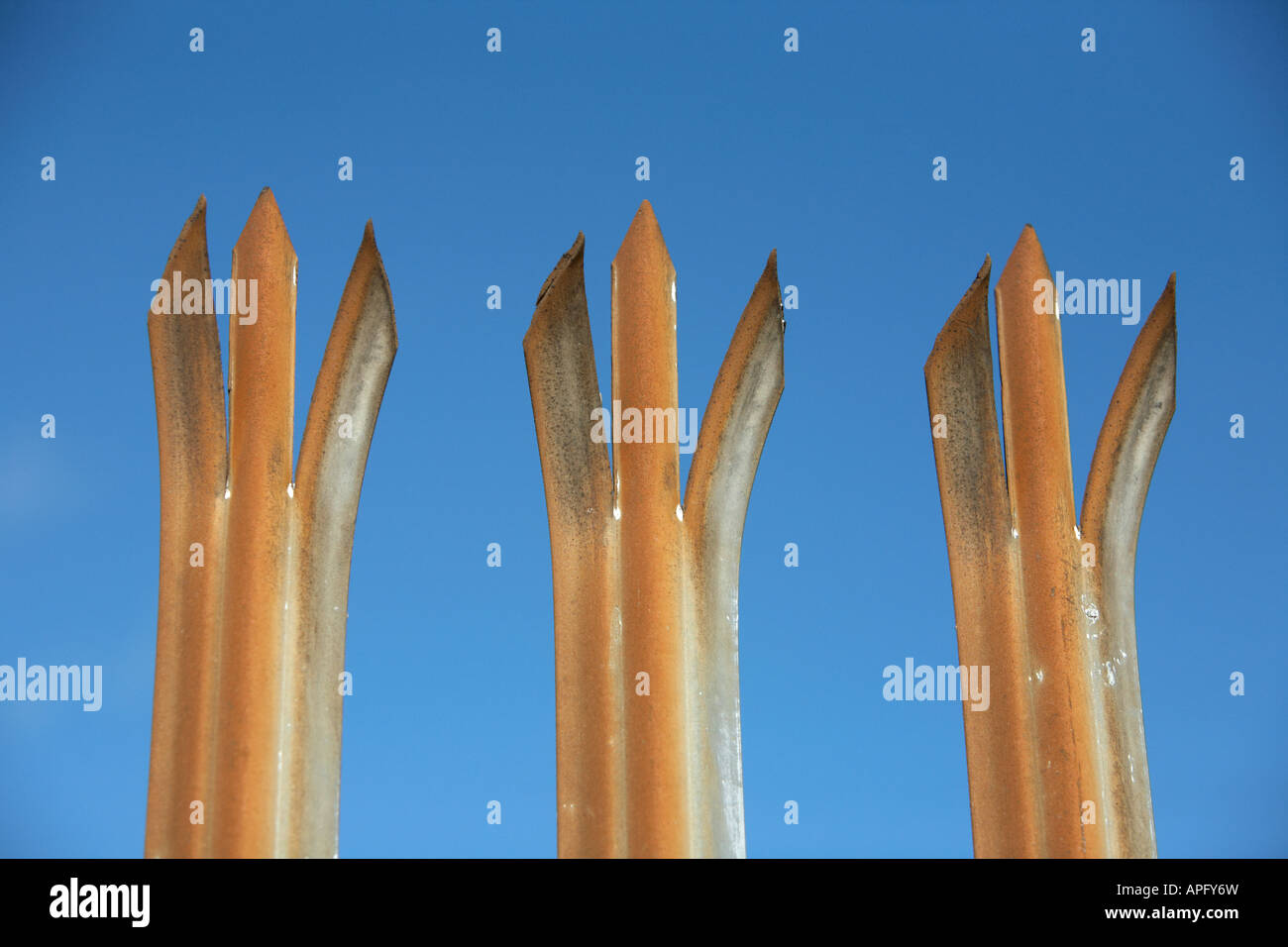 three spiked posts of a weathered metal security fence Belfast county