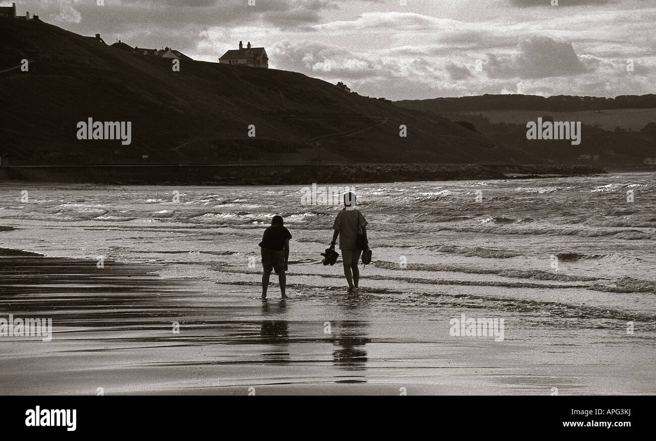 Silhouette of two people walking along the beach in the evening on ...