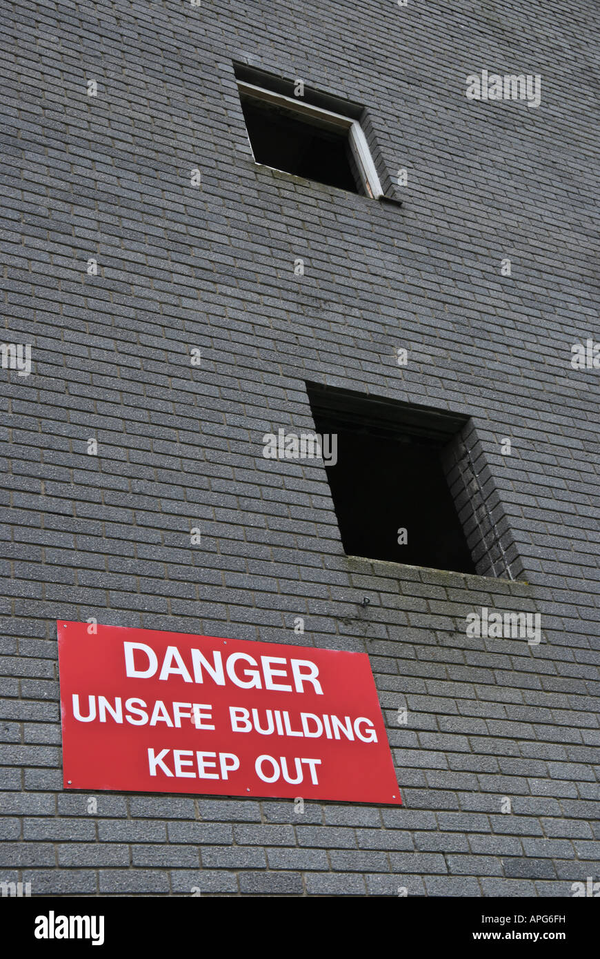 A derelict building with a warning sign 'Danger unsafe building keep out' Stock Photo
