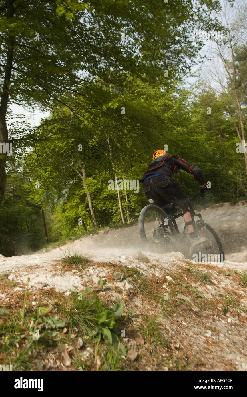 downhill mountain biker, landing with a puff of dust from his rear wheel Stock Photo