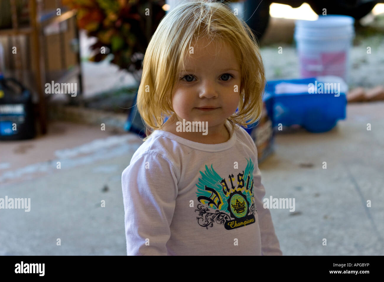 Adorable Girl Blue-Eyed Blonde Haired Toddler in a Messy Room Stock Photo