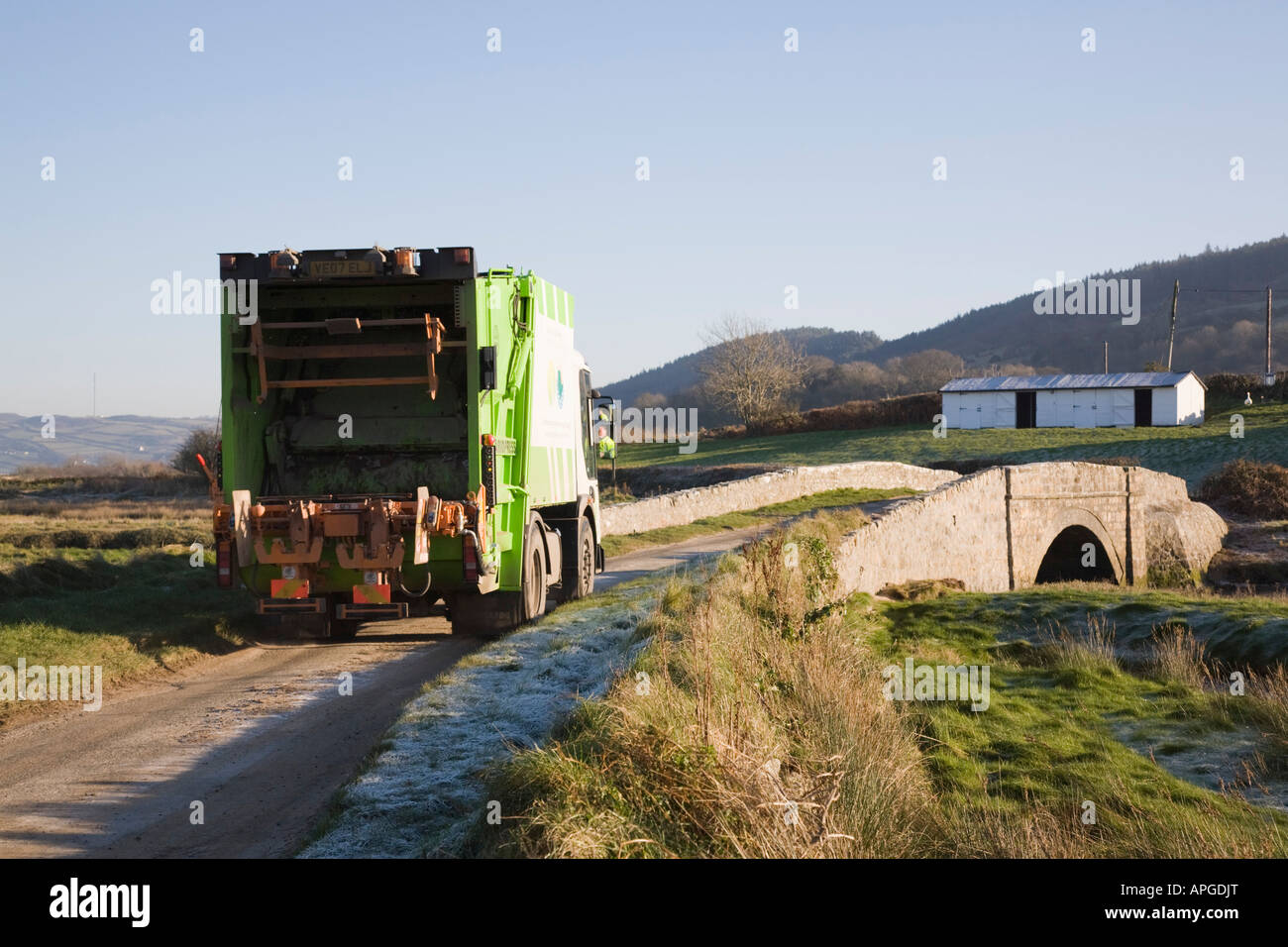 Council Local Authority domestic dustbin refuse collection lorry driving on narrow rural country road bridge Anglesey North Wales UK Stock Photo