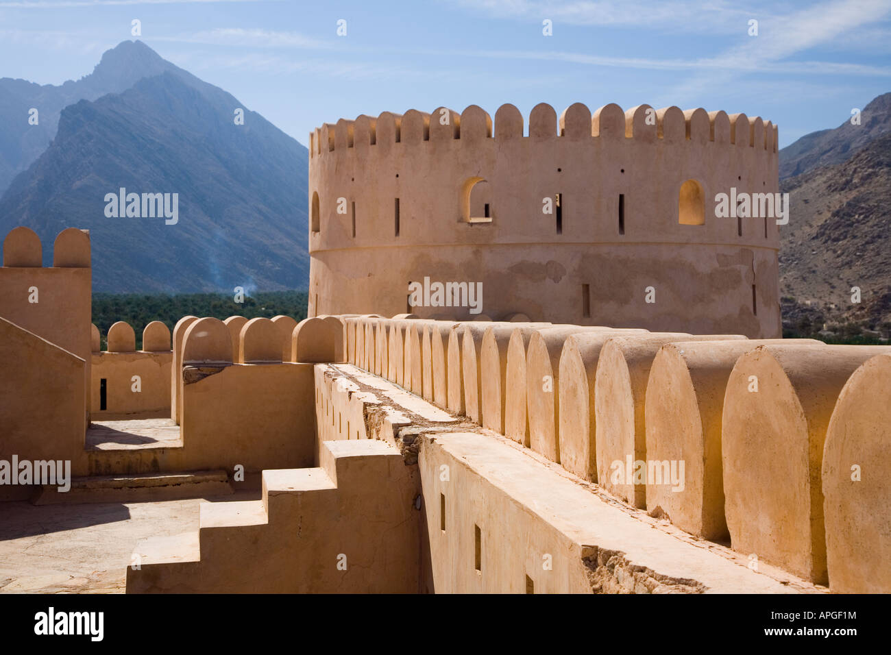 Battlements and tower of Nakhal Fort with mountains beyond in the Sultanate of Oman Stock Photo