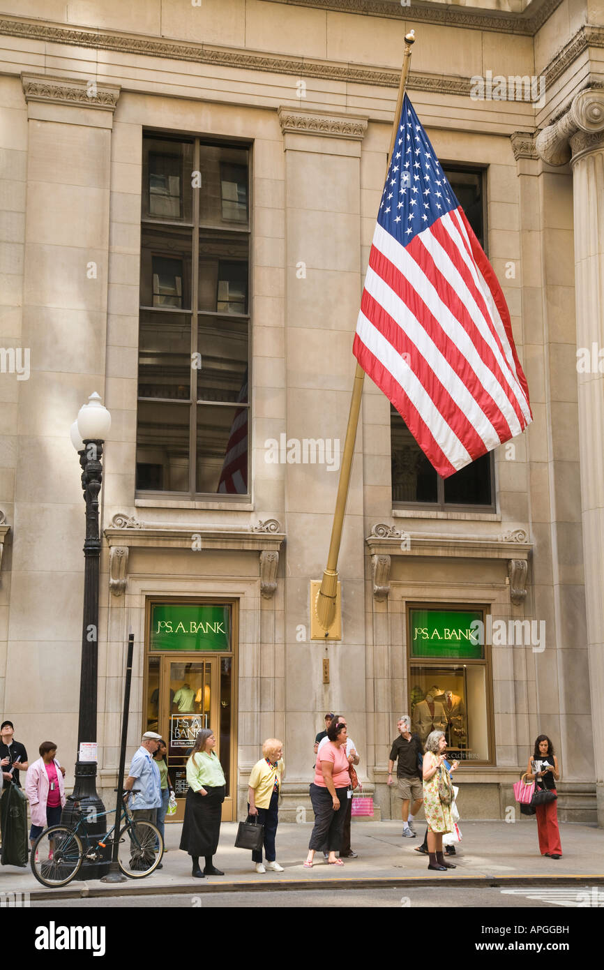 ILLINOIS Chicago People waiting at bus stop on LaSalle Street, American flag, financial district, sidewalk Stock Photo