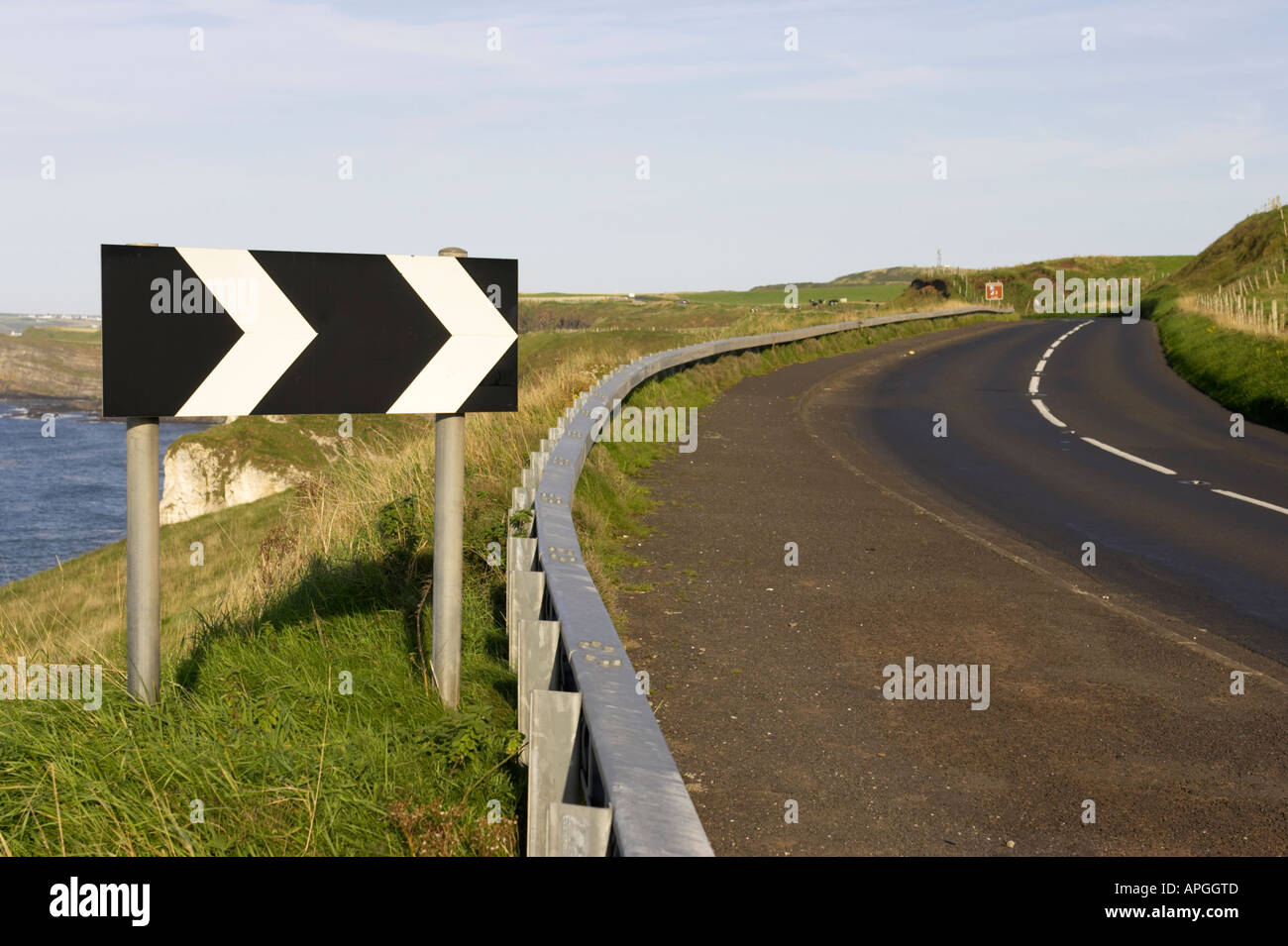 black and white chevron sharp deviation to the right road sign near dangerous bend on cliffs on the A2 coast road near Dunluce Stock Photo