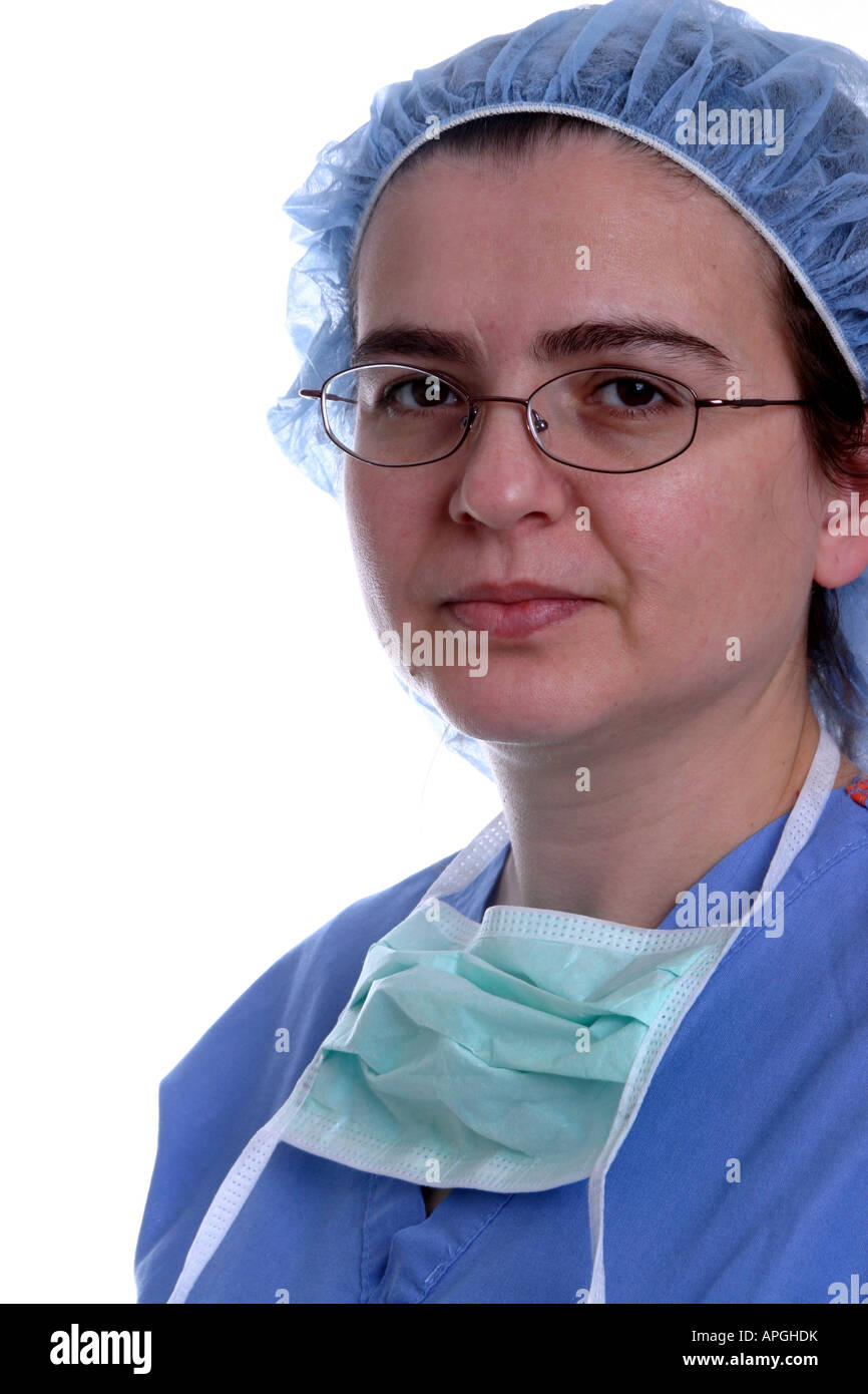 A nurse or surgeon wearing scrubs, glasses, hair bonnet, and surgical mask around her neck Stock Photo