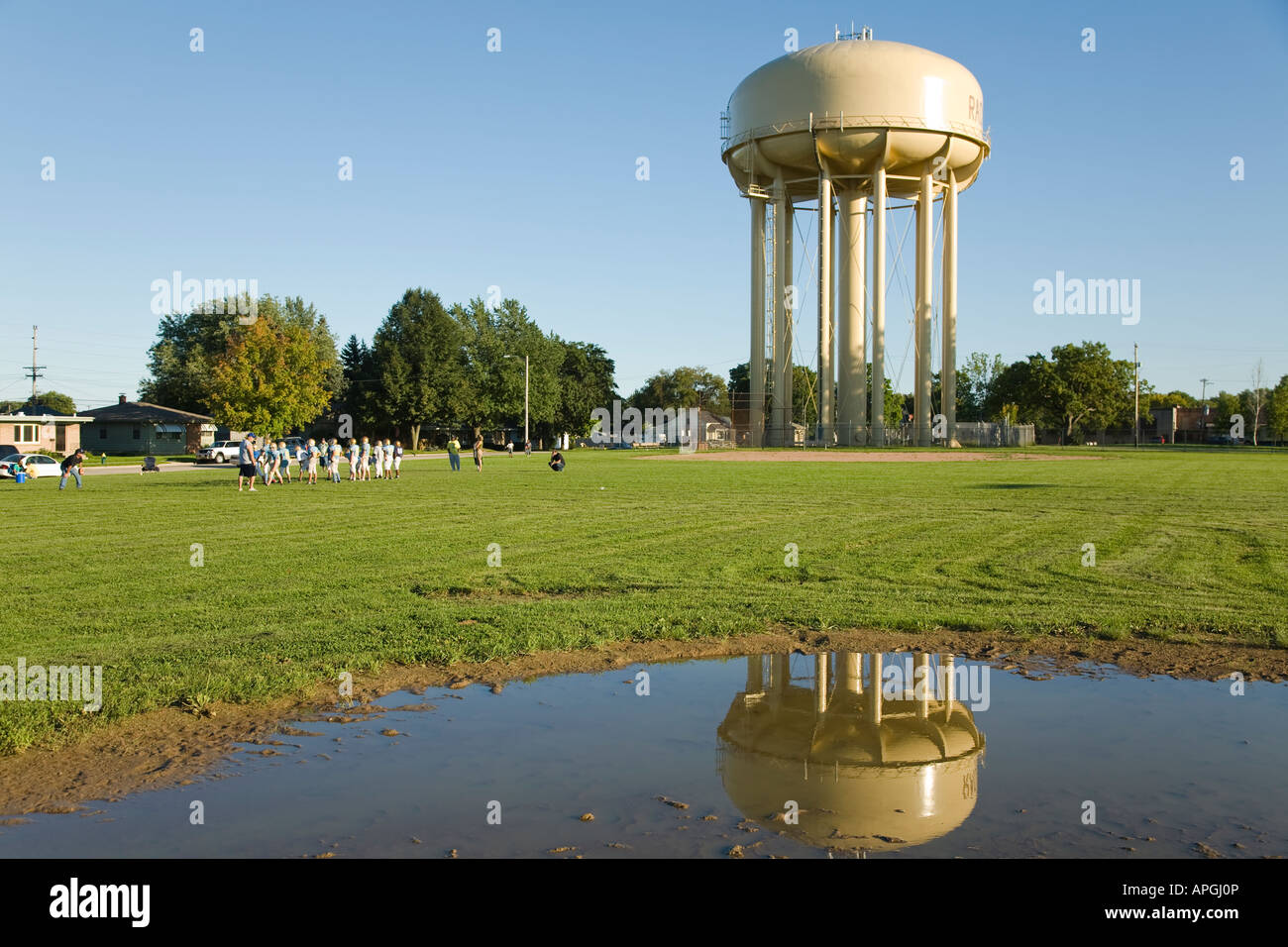 WISCONSIN Racine Middle school students having football practice field near water tower reflection in puddle in grass Stock Photo