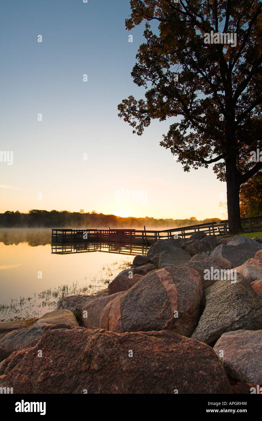 Sunrise on Hyland Lake in Bloomington Minnesota from rocky shoreline with fishing dock and fog Stock Photo