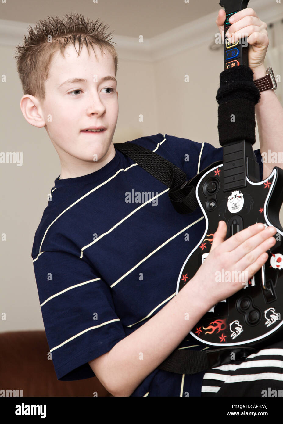 Youth playing Guitar Hero console game Stock Photo