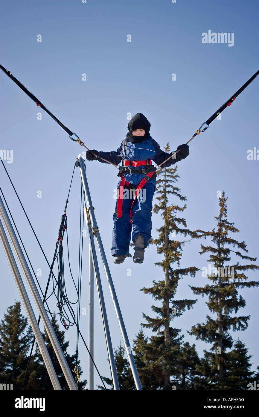 A child jumping on trampoline secured with jumping ropes Stock Photo