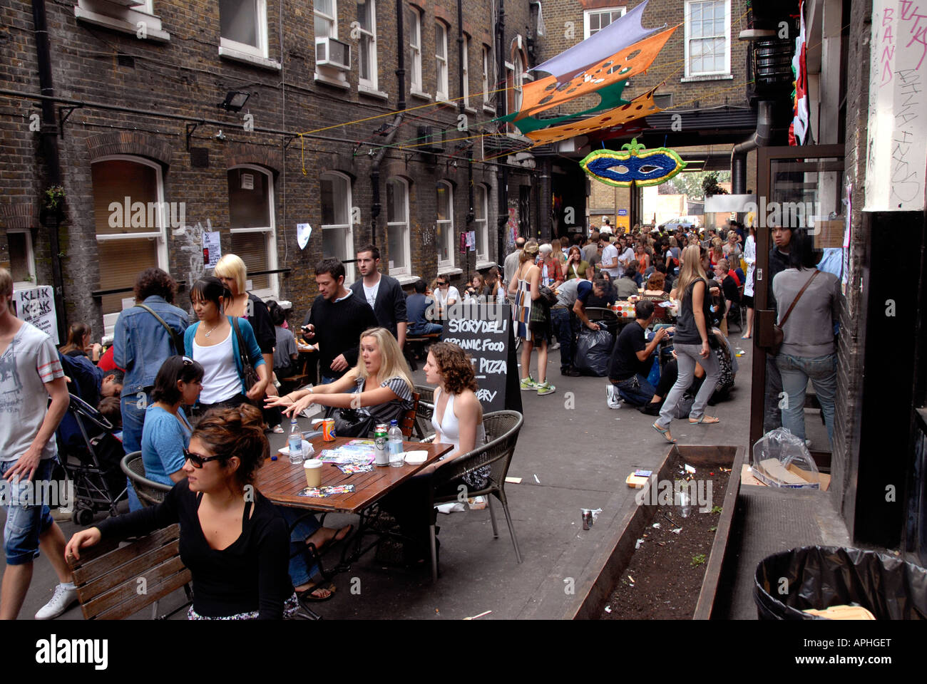 Young people eating drinking outside pub off Brick Lane East End London. Stock Photo