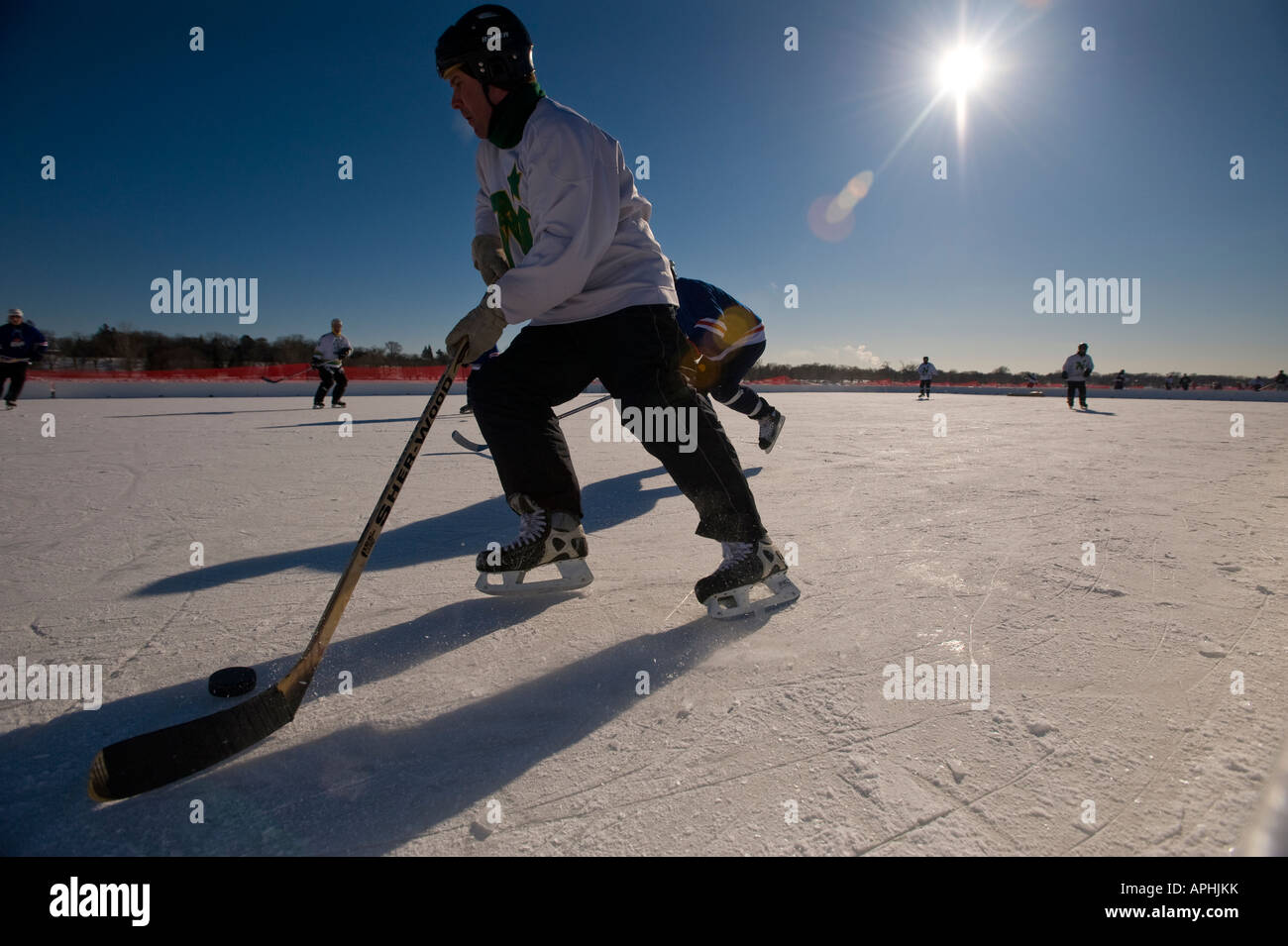 A HOCKEY PLAYER BRINGS THE PUCK DOWN THE SIDE OF THE RINK US POND
