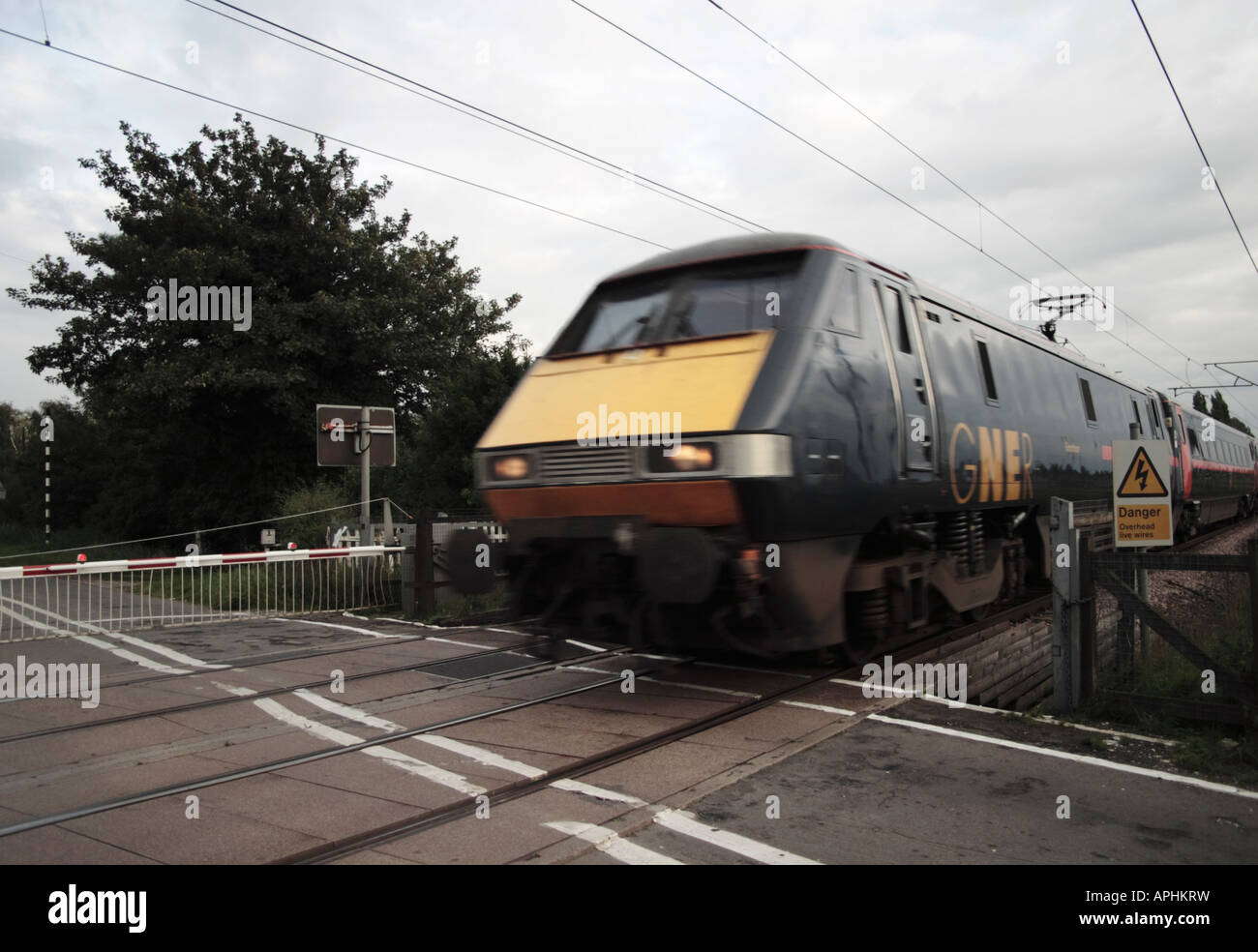 Passenger train speeding through a level crossing on the east coast main line. Stock Photo