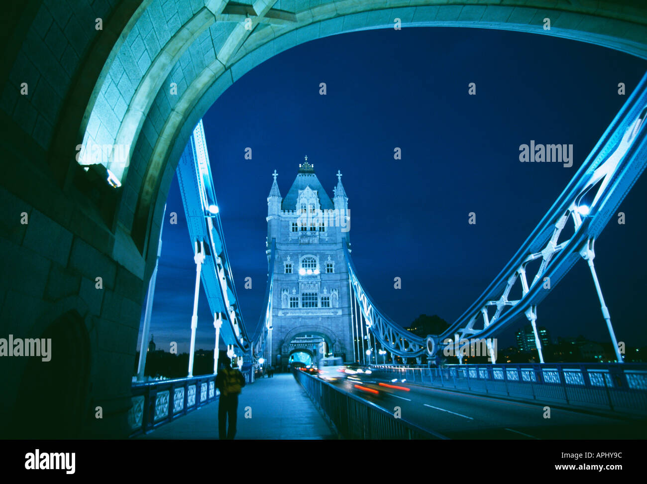 Night time view of Tower Bridge with traffic crossing London The architect Sir Horace Jones died in 1887 before the foundations were complete and the task passed to his assistant George Daniel Stevenson who had an even greater passion for Victorian Gothic style Opened in 1894 linking the Tower of London and the south bank across the River Thames The bridge opens to allow large river craft to pass underneath Stock Photo