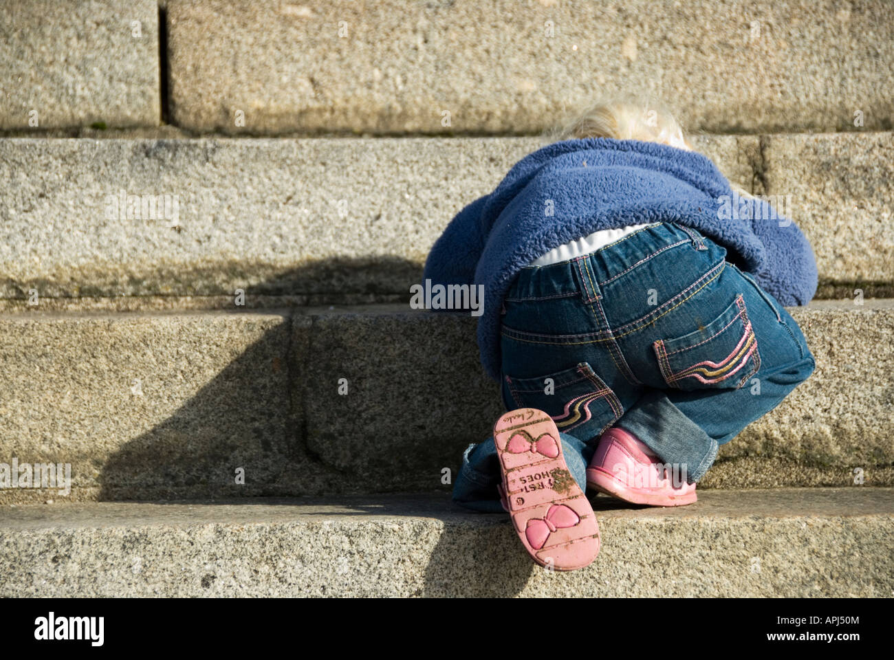 Stock Photo of a two year old toddler climbing very carefullu backwards down a row of steps Stock Photo