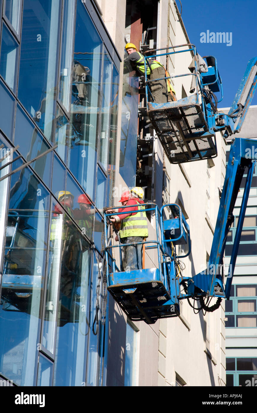 Construction workers using sky lift crane at office block, Limerick Stock Photo