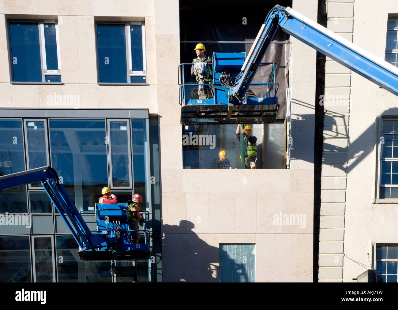 Construction workers using sky lift crane at tenement block, Limerick Stock Photo